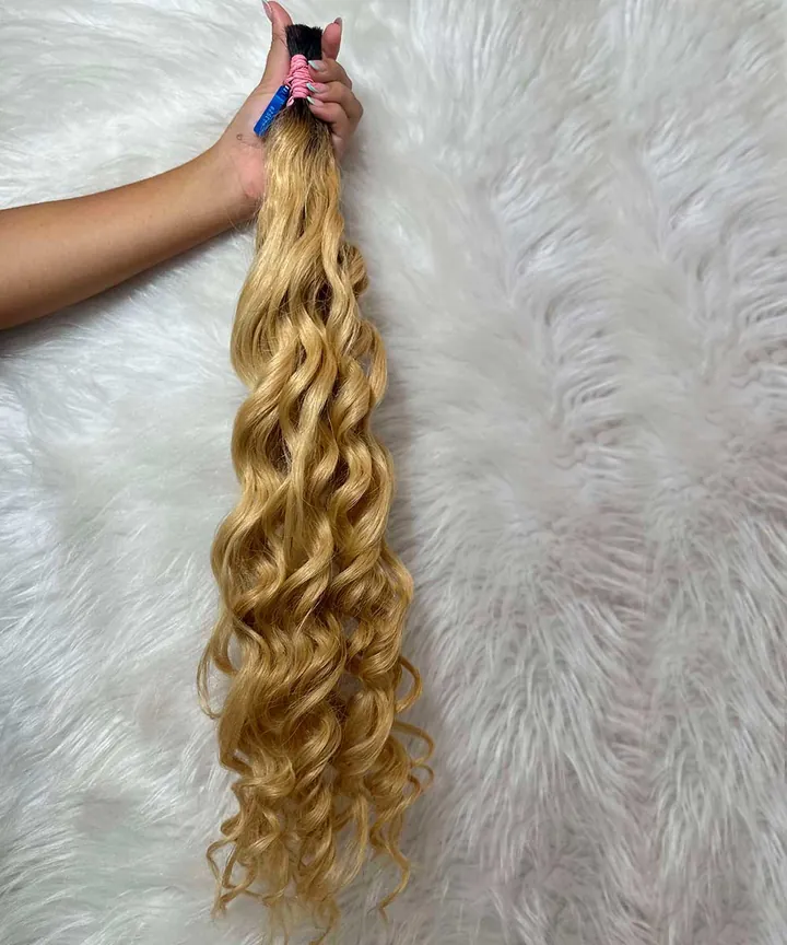 Mão segurando um cabelo humano loiro e cacheado de 80 cm